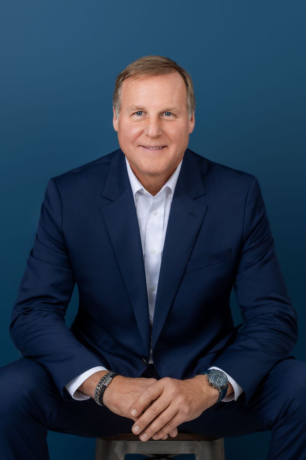 Professional business portrait series of person in navy suit against dark blue background showing different poses.