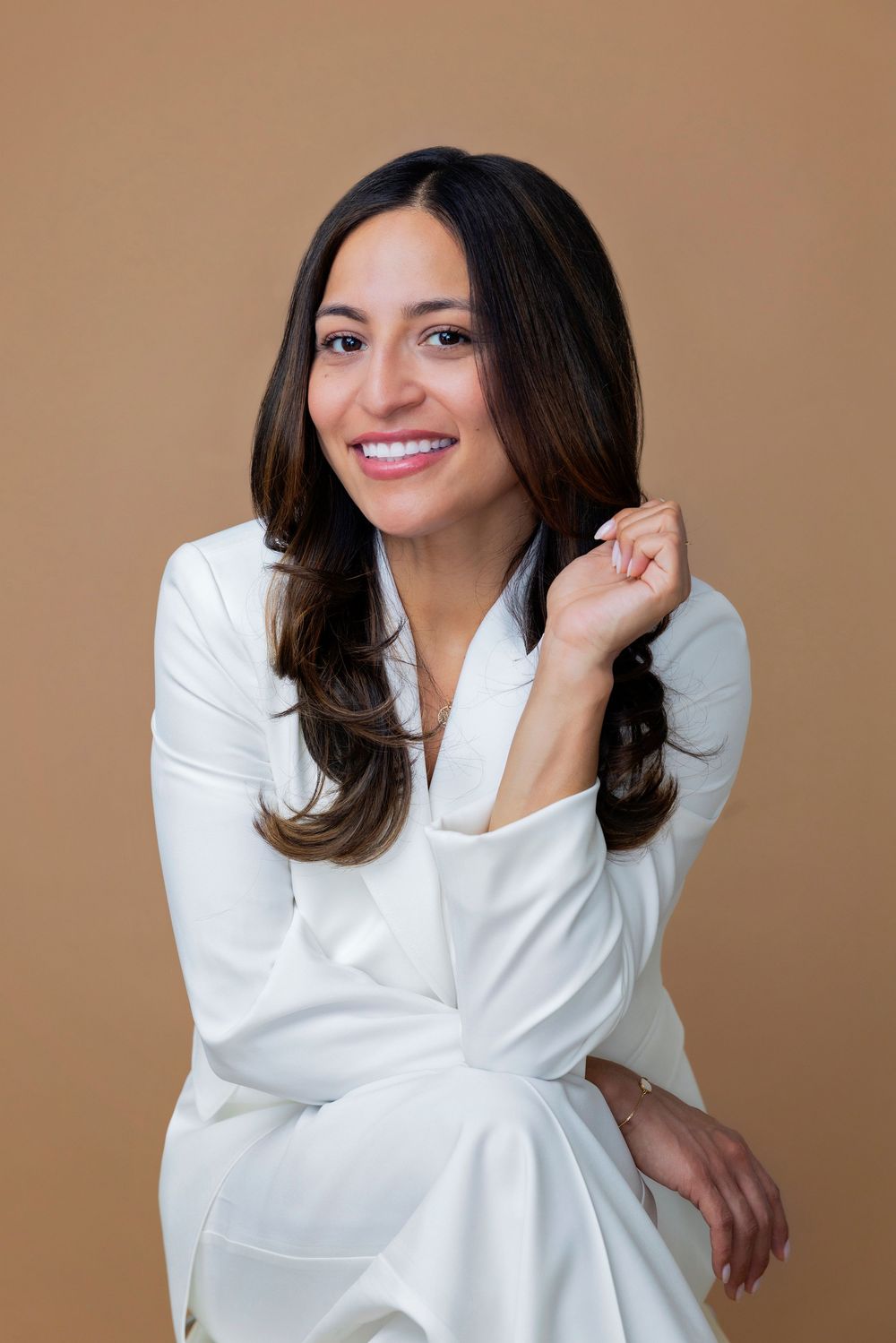Model wearing a stylish white long-sleeved blouse poses elegantly against a brown background in multiple poses.
