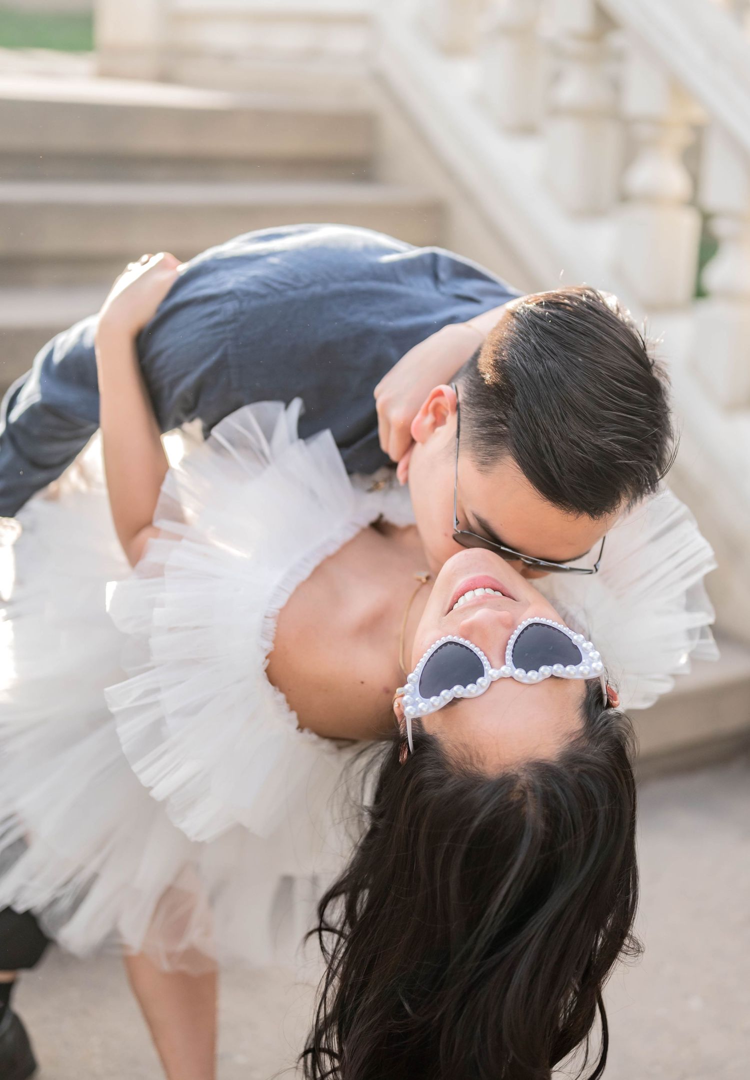 Romantic dip kiss on stone steps with bride in tulle skirt.