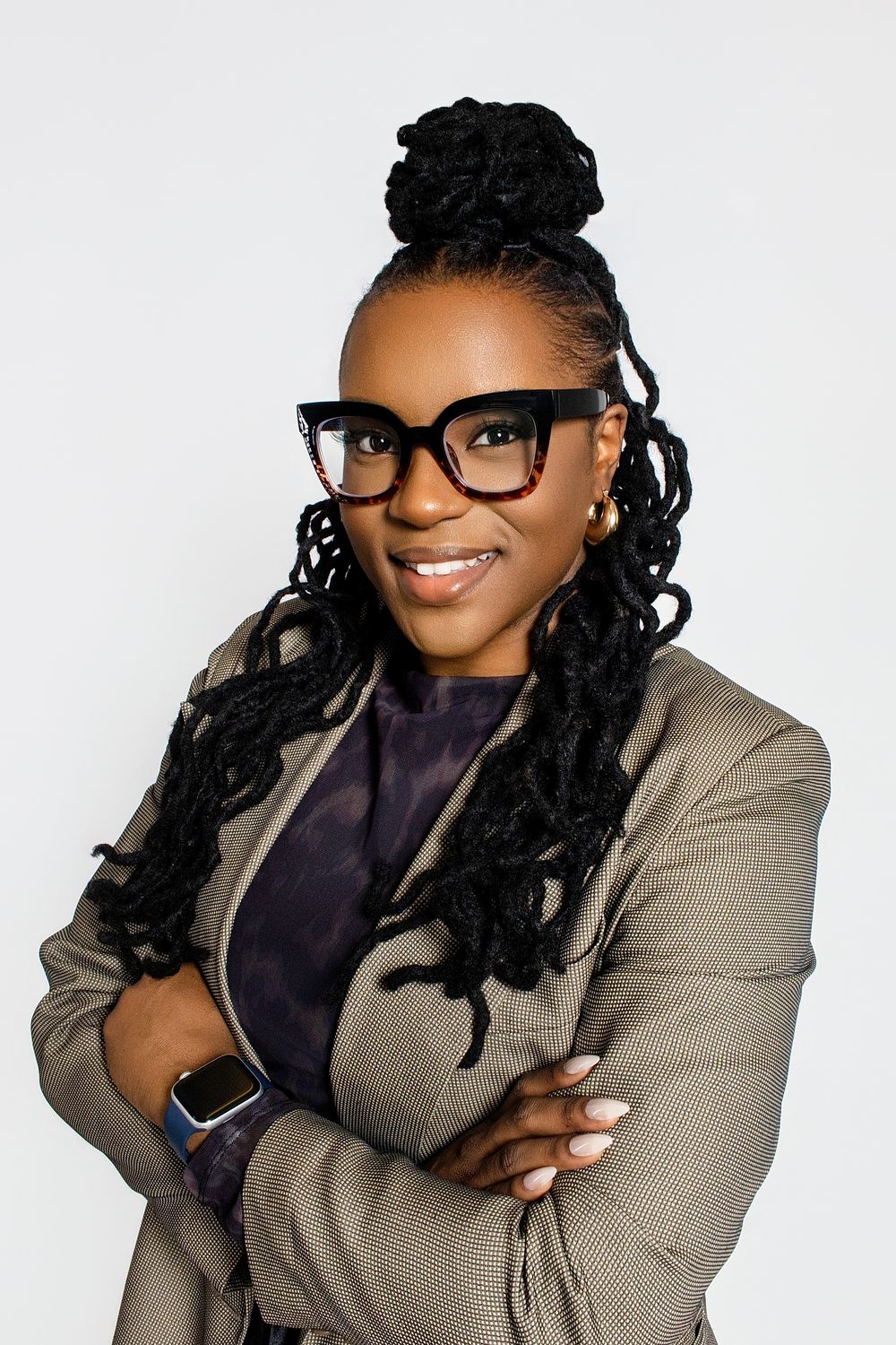 Professional headshot wearing a gray blazer and black top with glasses against a white backdrop.