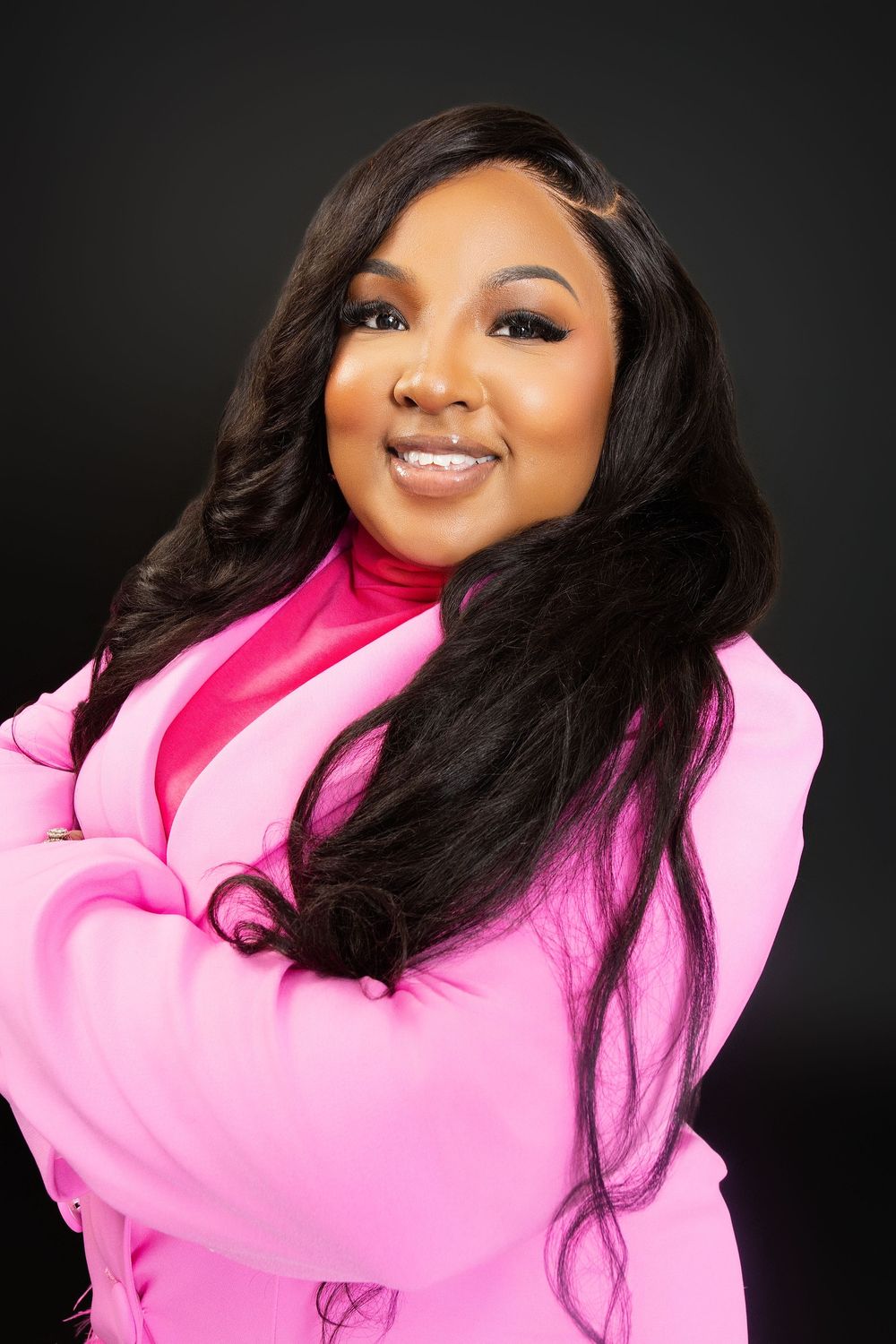 A joyful portrait featuring a bright pink blazer and flowing dark hair.