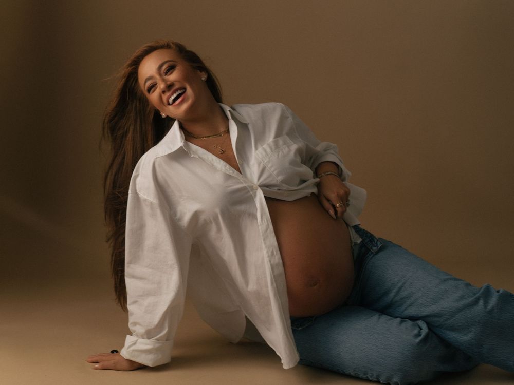 Person in white button-up shirt and blue jeans poses artistically while lying down in a studio setting.