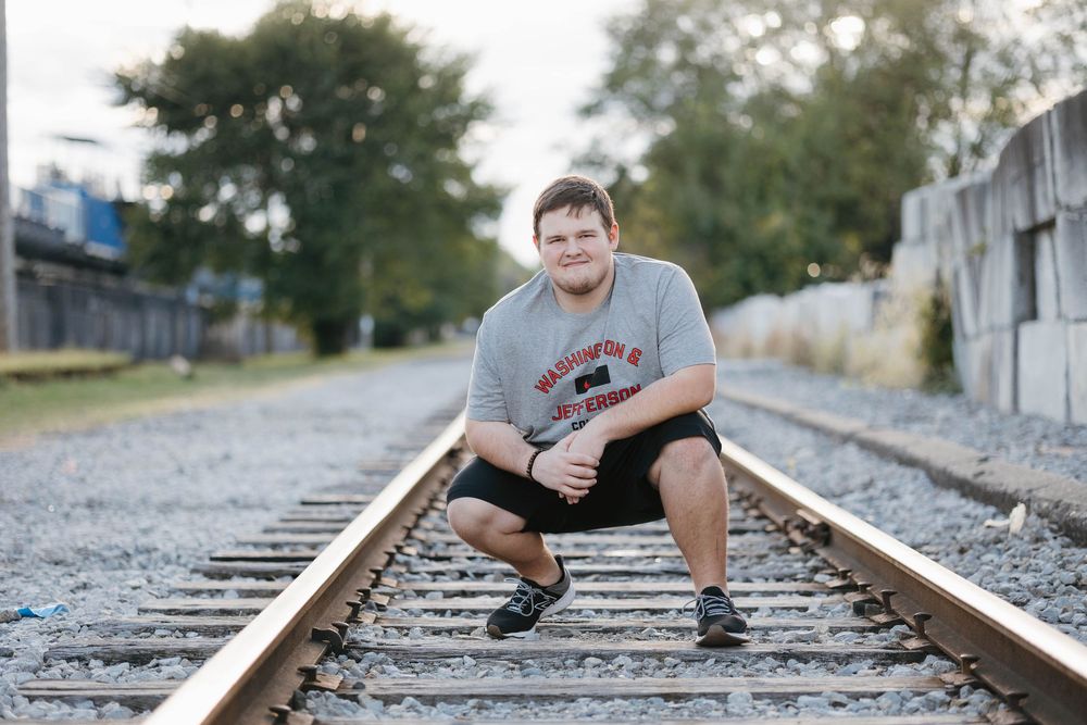 High school senior posing on railroad tracks for senior pictures.