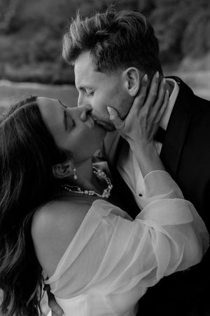 An intimate black and white portrait of a romantic embrace in formal attire.