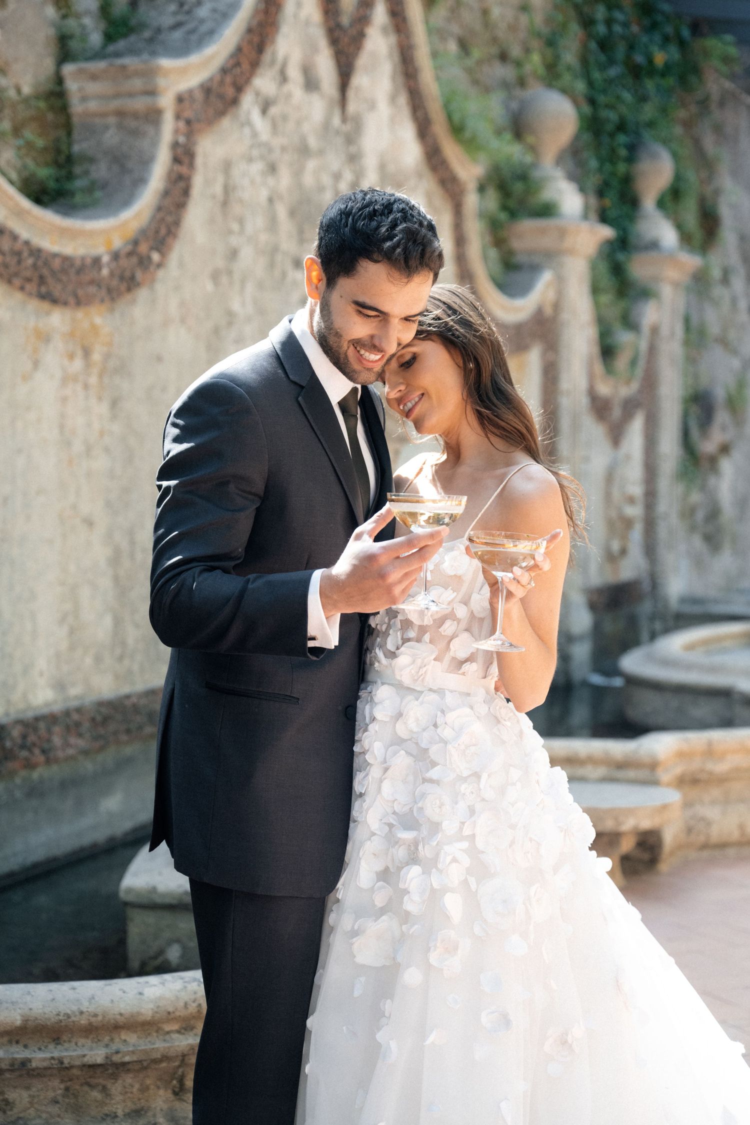 Newlyweds share a joyful moment together on an ornate stone terrace with decorative architectural elements.
