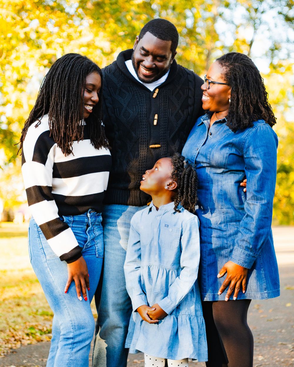 Family sharing joyful moment together outdoors with fall foliage backdrop.