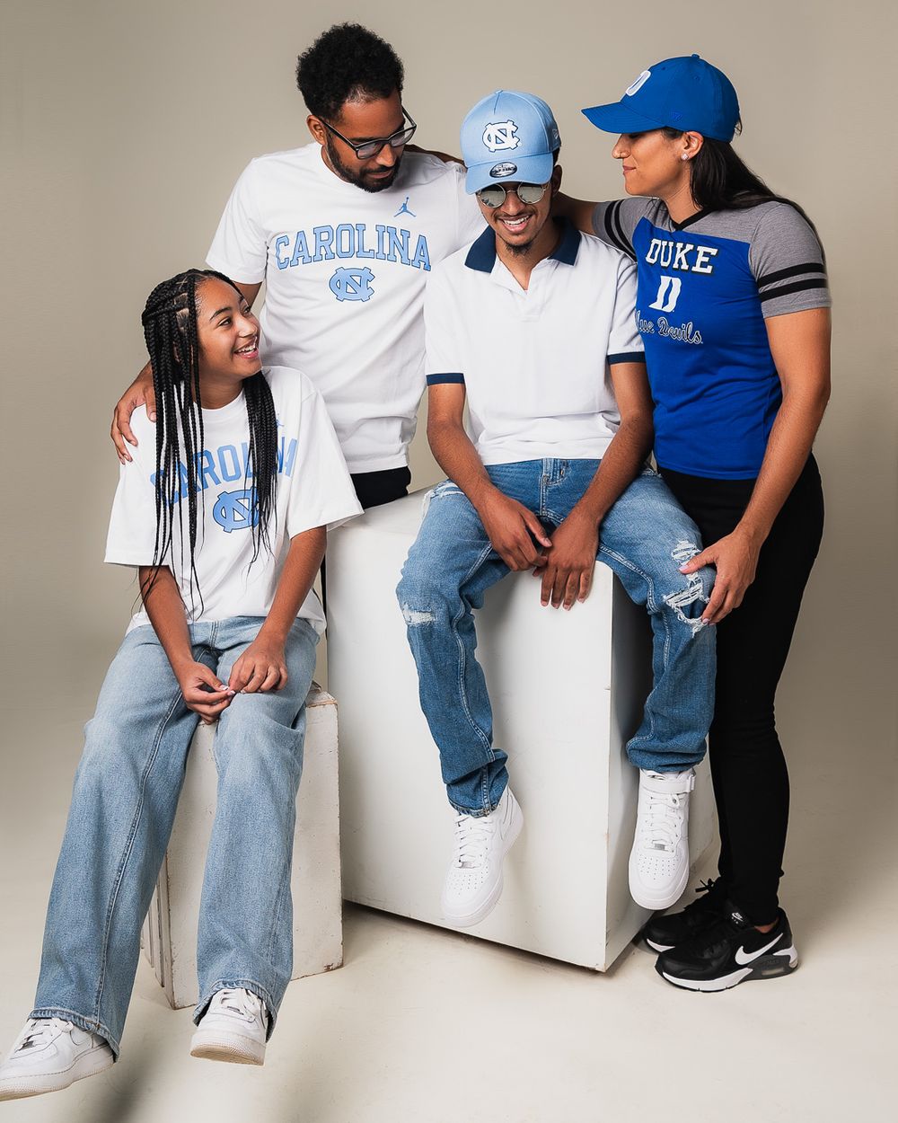 Group photo of four people wearing UNC and Duke athletics apparel.