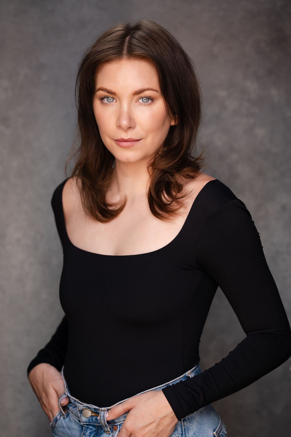 Professional studio portrait series showing someone in a black long sleeve top against a gray background.