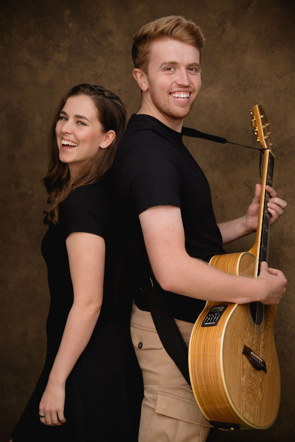 A sequence of playful poses with two people in black shirts holding an acoustic guitar against a dark backdrop.