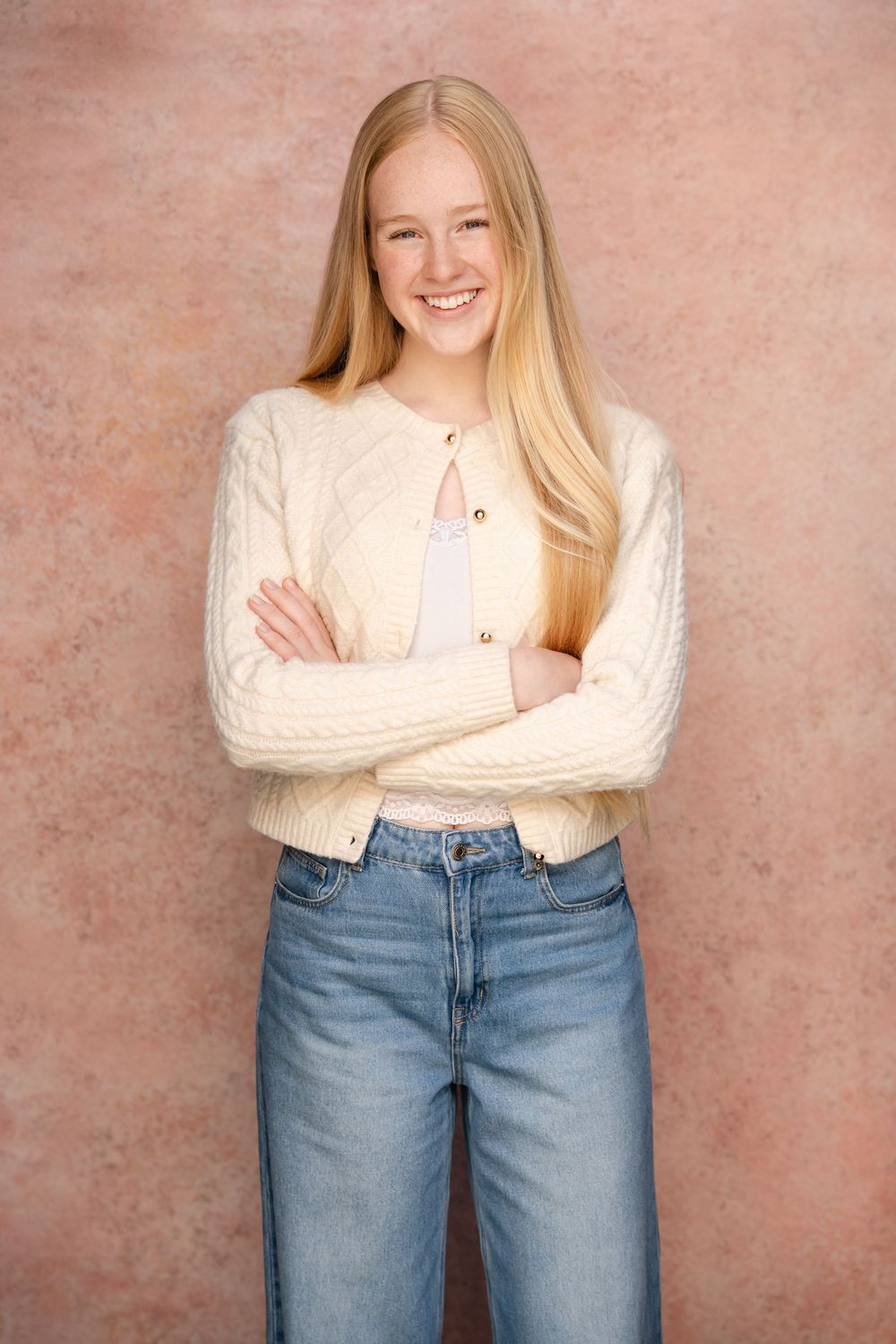 A sequence of casual portraits against a pink backdrop showing a cream sweater and light denim jeans outfit.