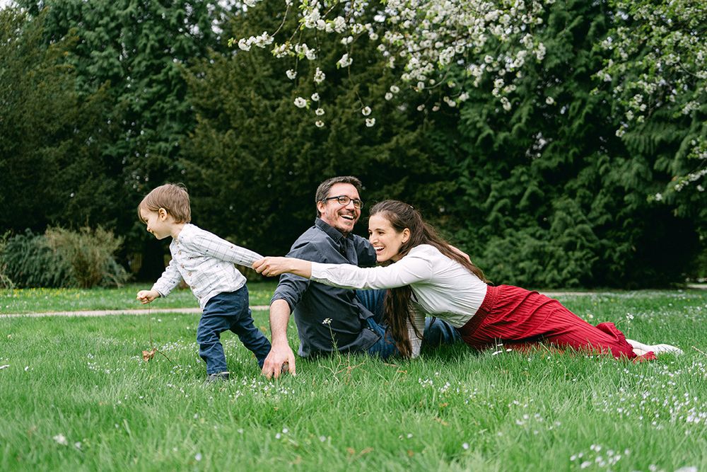 A family plays together on green grass in a garden setting.