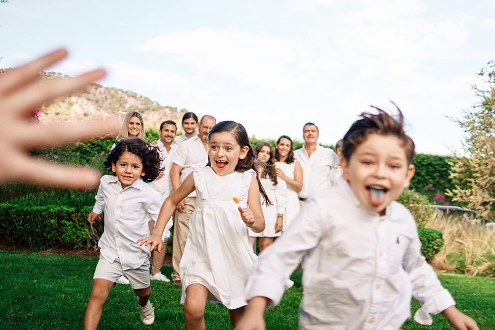 Joyful children running and playing outdoors with adults visible in the background.