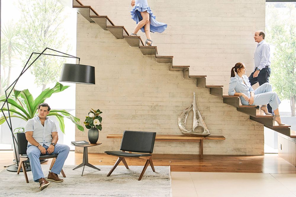 Modern home interior with floating wooden staircase and family members at different levels.