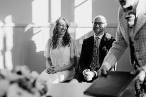 Black and white photo of a wedding ceremony with natural light streaming through windows.