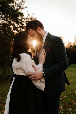 A romantic sunset silhouette of a couple embracing in a garden with golden light streaming between them.