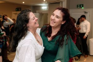 Two people in green and white outfits share a joyful moment of laughter together.