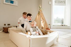 Family relaxing together in a bright white room with natural light streaming through windows.