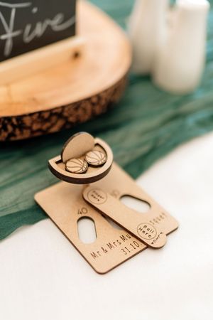 Wooden key ring with laser-engraved designs lying on a turquoise surface showing close-up details.