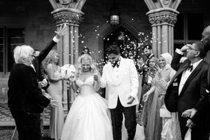 Black and white photo of a bride and groom exiting a church ceremony as guests celebrate with confetti.