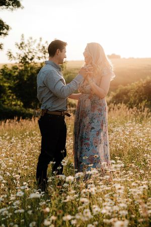 Couple sharing tender moments in a sun-drenched field of white wildflowers at golden hour.