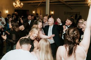 Guests dancing joyfully at a wedding reception in an elegant venue with chandeliers overhead.