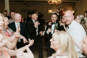 Guests celebrating and dancing joyfully at a wedding reception in an elegant venue.