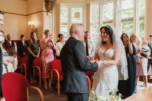 Wedding guests celebrate during an indoor ceremony at an elegant venue.