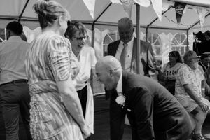 Wedding reception guests dancing under white bunting decorations.