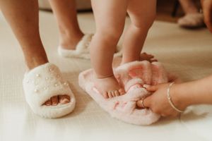 Cozy scene of feet in fluffy pink slippers on a light carpet.