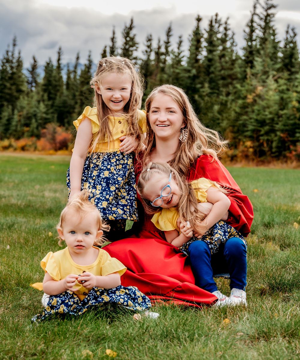 Group portrait on grass with evergreen forest and mountains in background.