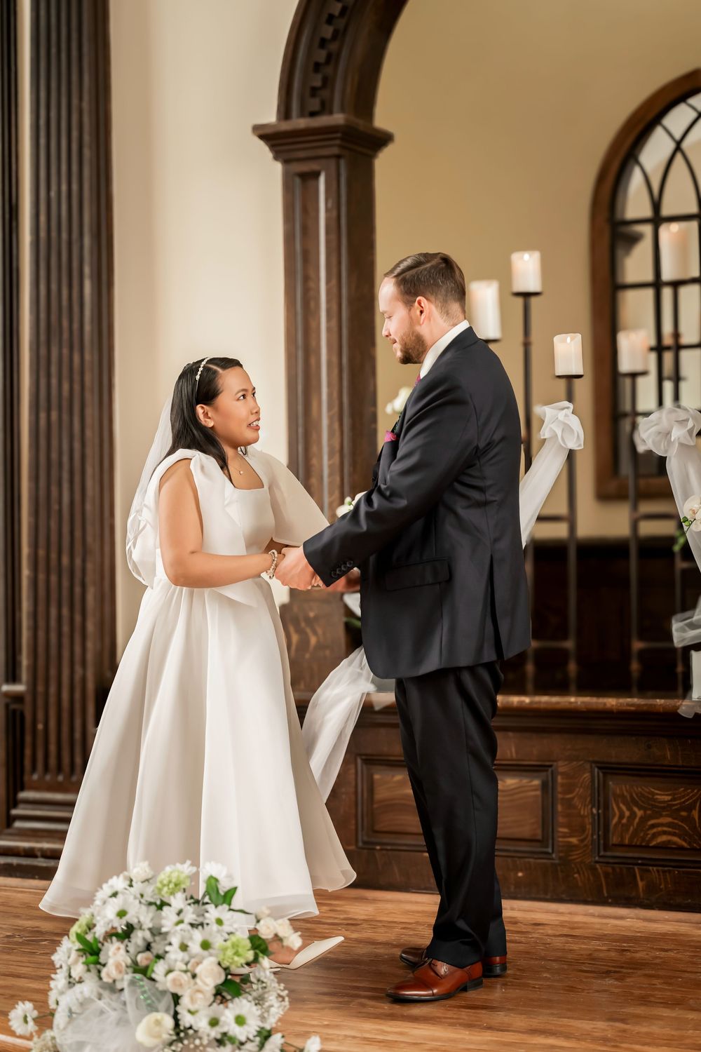 Bride and groom holding hands at the altar during their wedding ceremony in an elegant church.