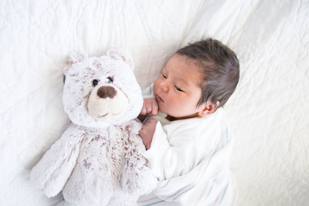 Newborn baby sleeping peacefully next to a soft teddy bear during her Fresh 48 session at Fort Sanders Medical Center in Knoxville.