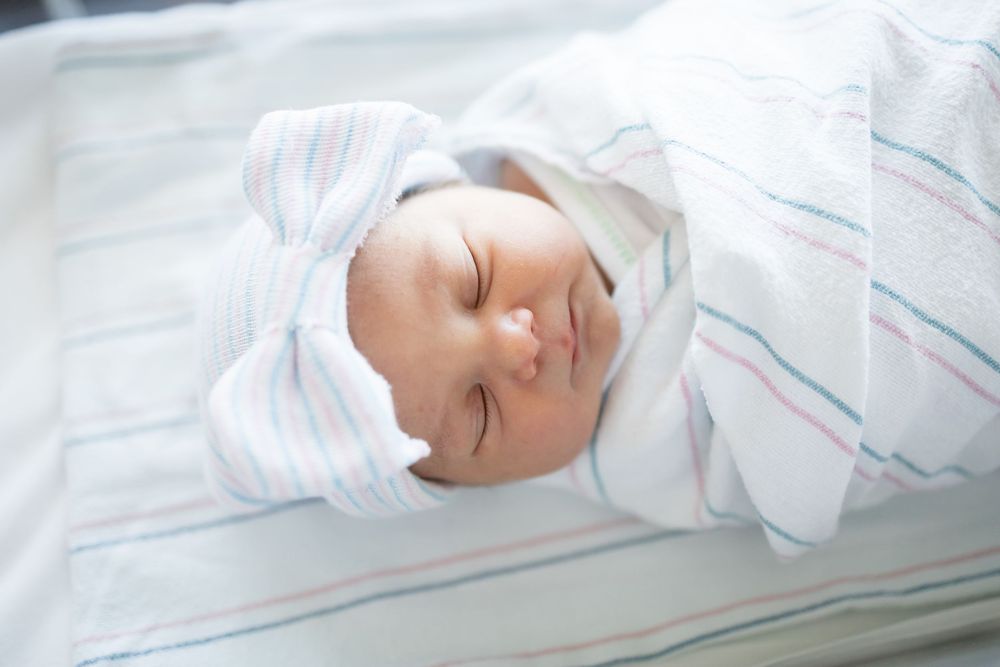 Newborn baby swaddled in striped blanket during her Fresh 48 session at Fort Sanders Medical Center in Knoxville.