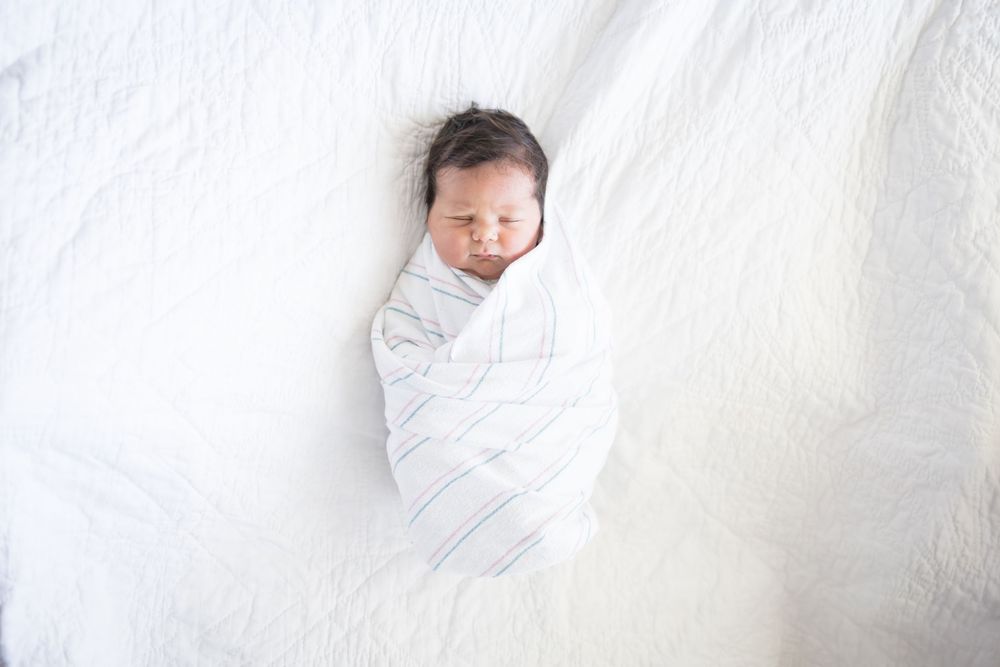 Newborn baby swaddled in white striped blanket during her Fresh 48 session at Fort Sanders Medical Center in Knoxville.