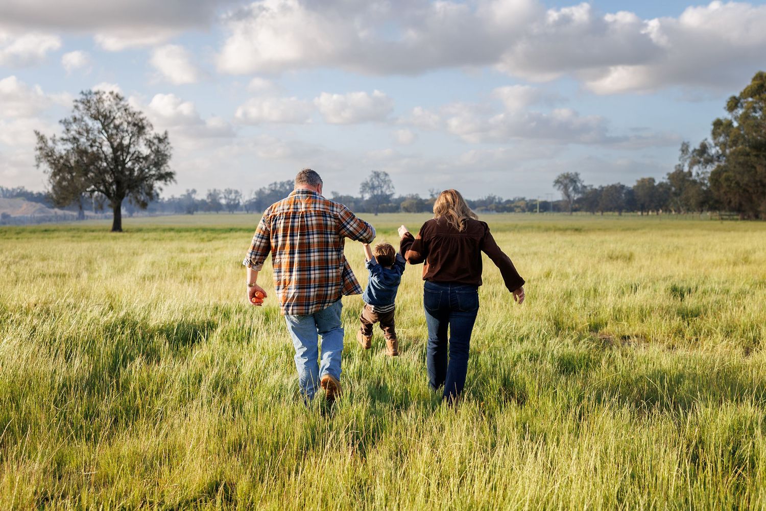 Family walking in lush, green paddock during a photo session in Perth
