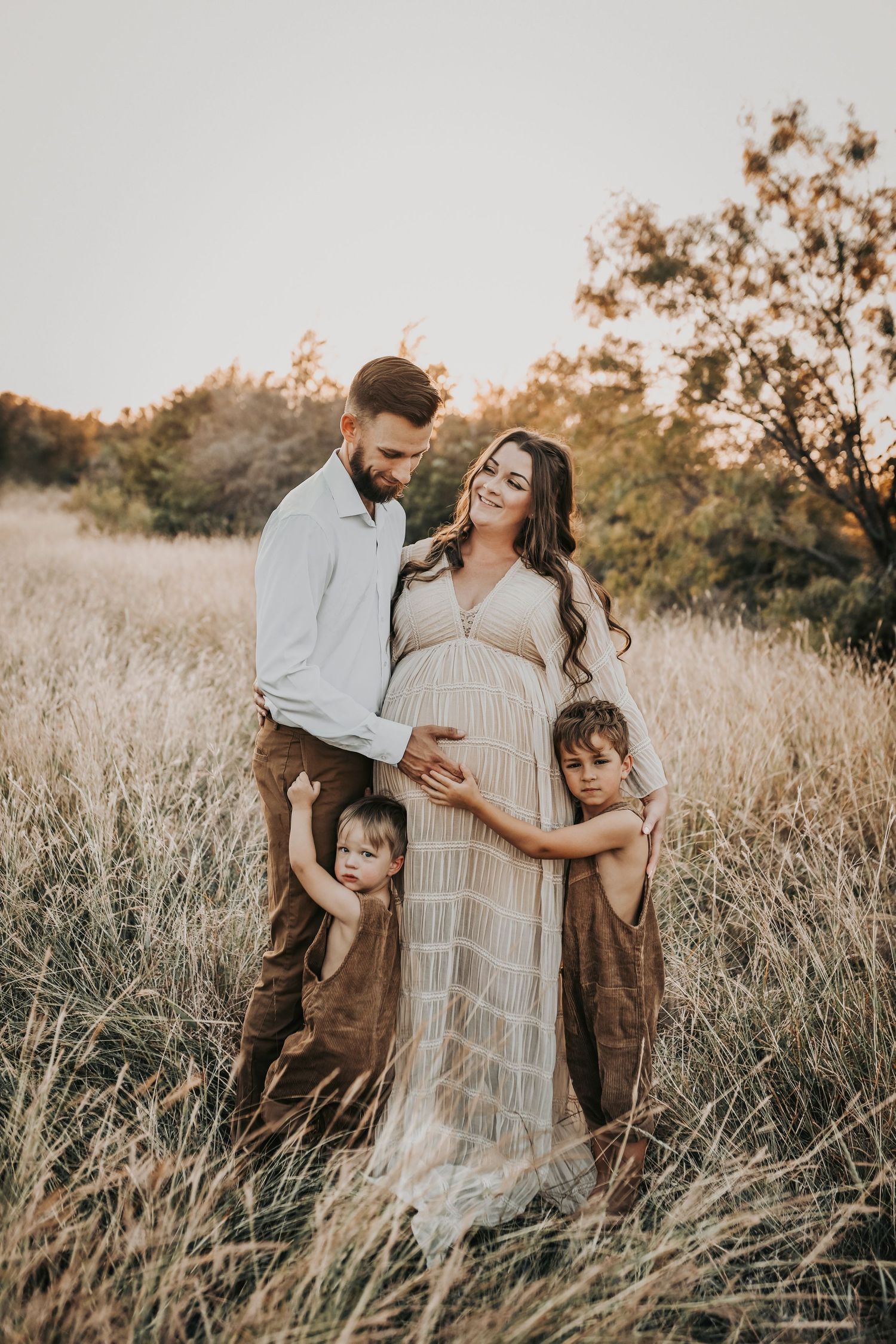 Candid family maternity photo of parents laughing and playing with their two boys