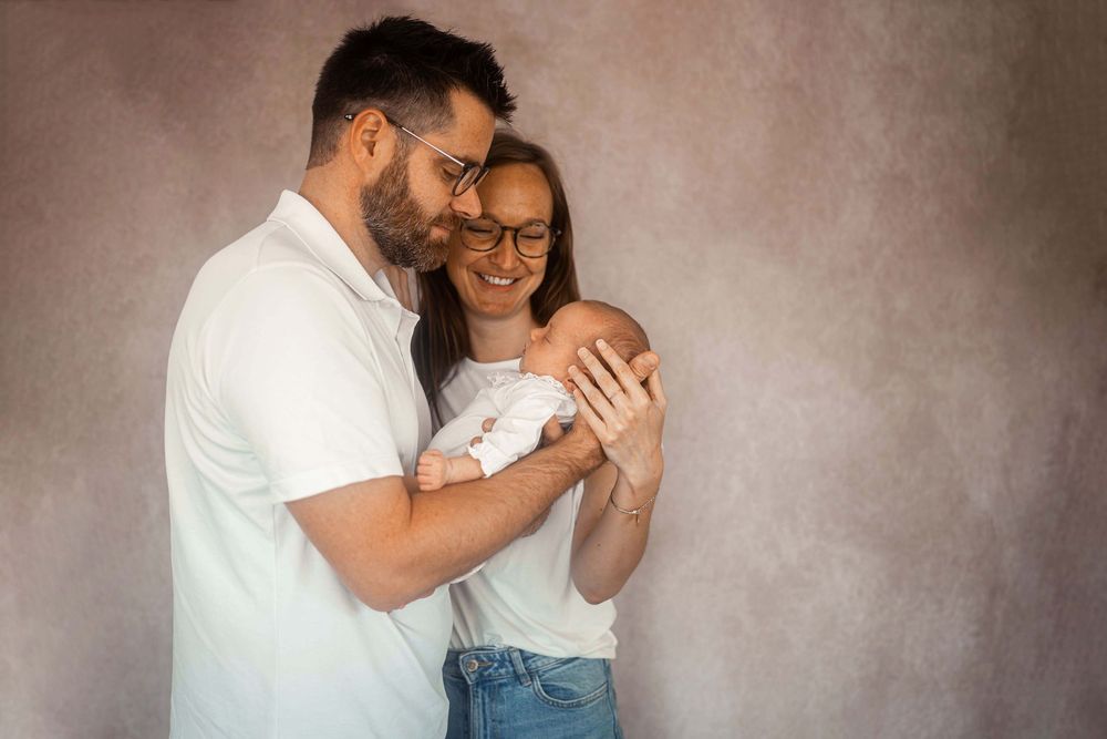 Des parents heureux,  sourient à leur nouveau-né dans un studio photo