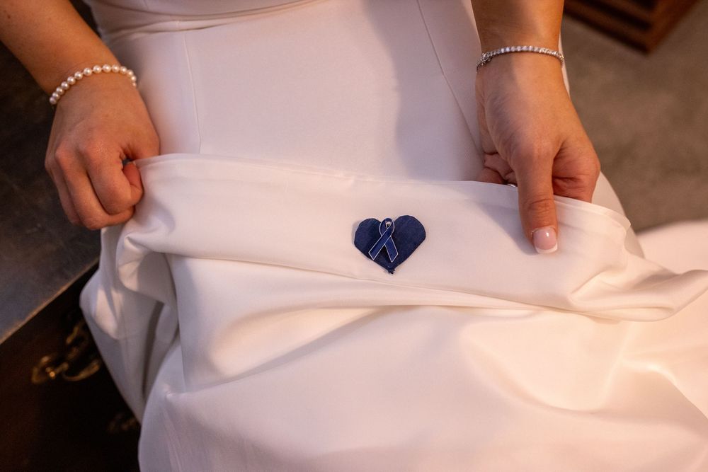 Bride holds wedding dress revealing a sewn-in navy blue heart embroidery as a sentimental something blue.