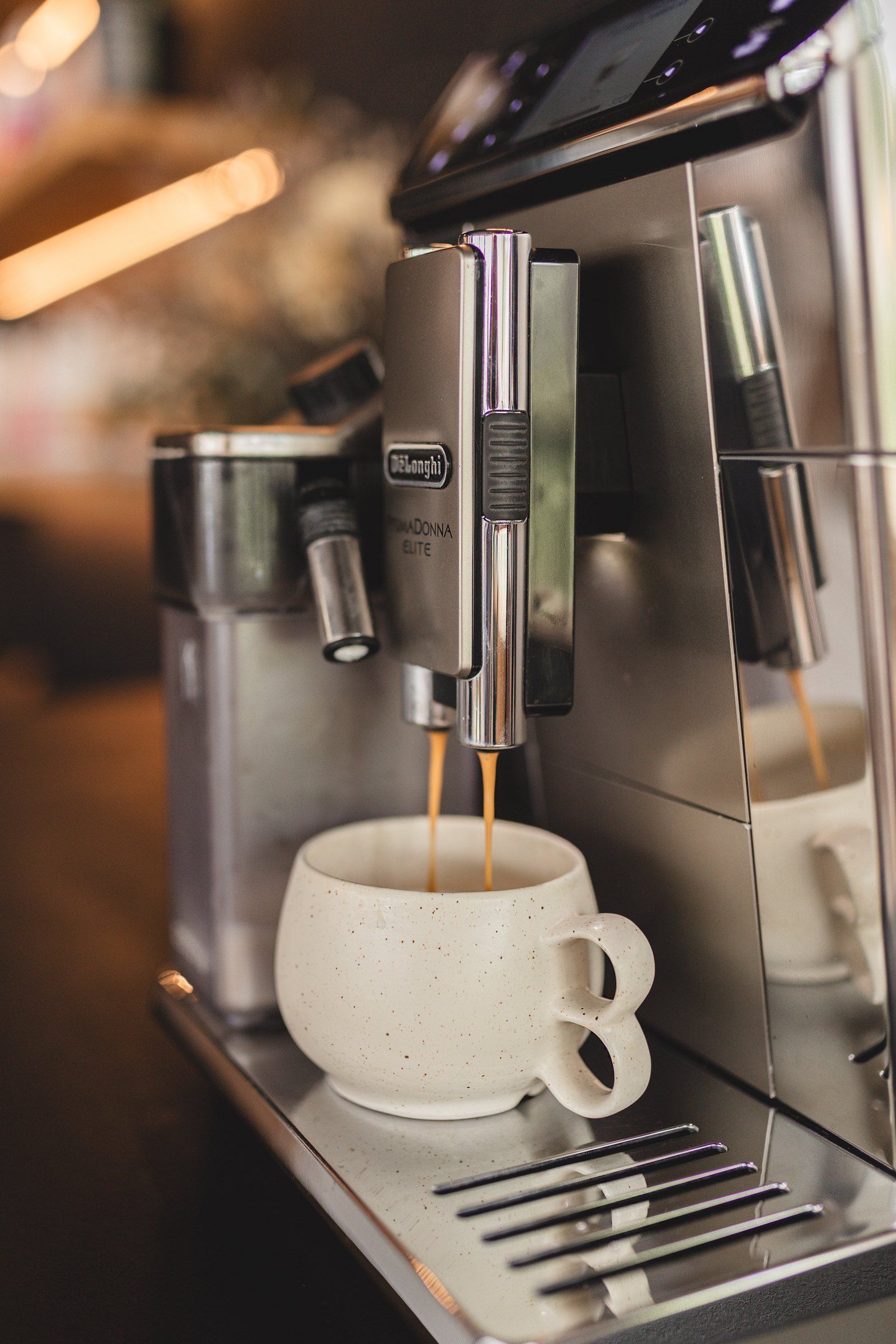 Yrityskuvaus omissa tiloissa. Espresso-kahvinkoneesta valuu kahvia kauniiseen keraamiseen kahvikuppiin.