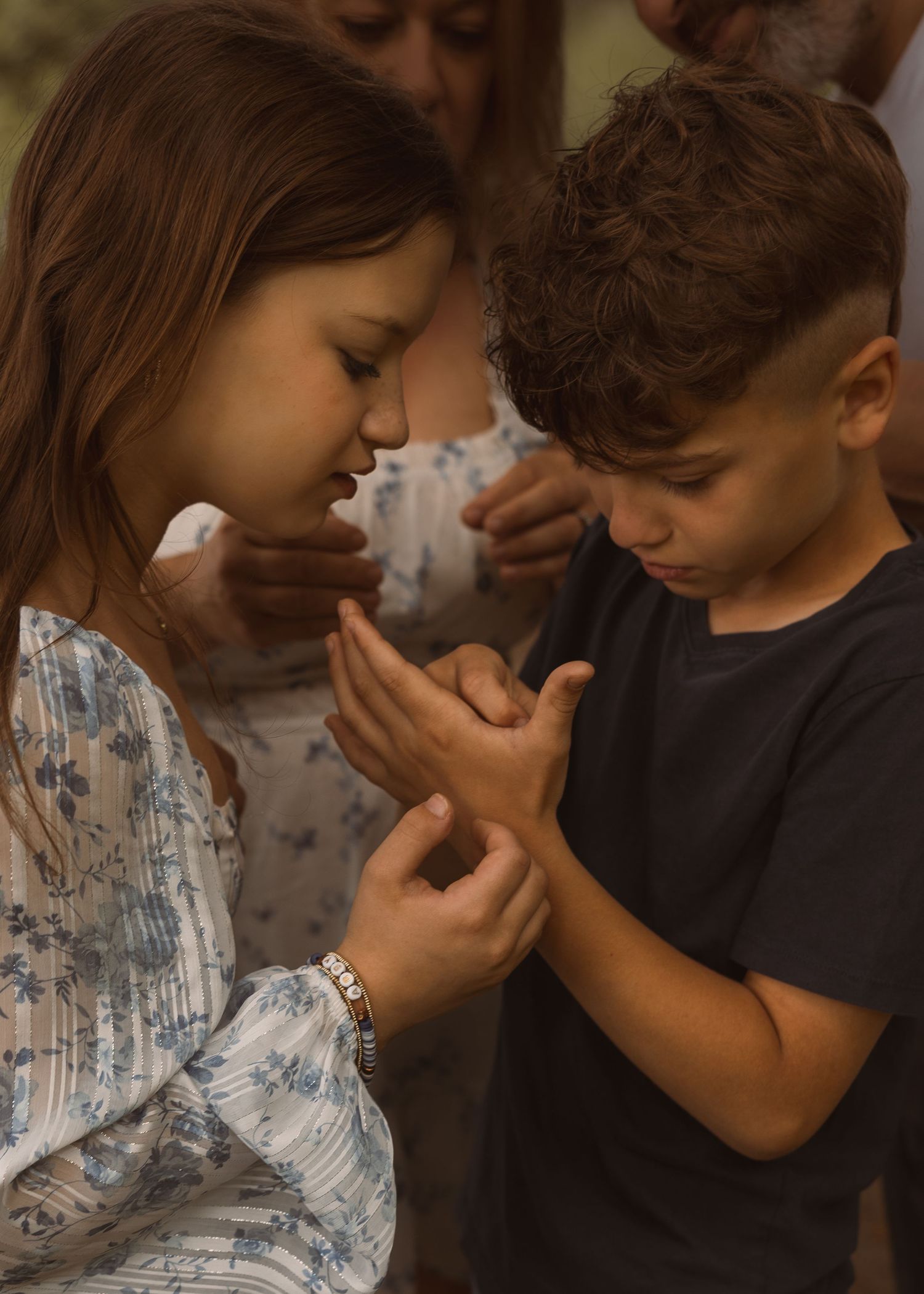 Two children holding hands together in a heartfelt moment, wearing casual clothing in a warm, candid setting.