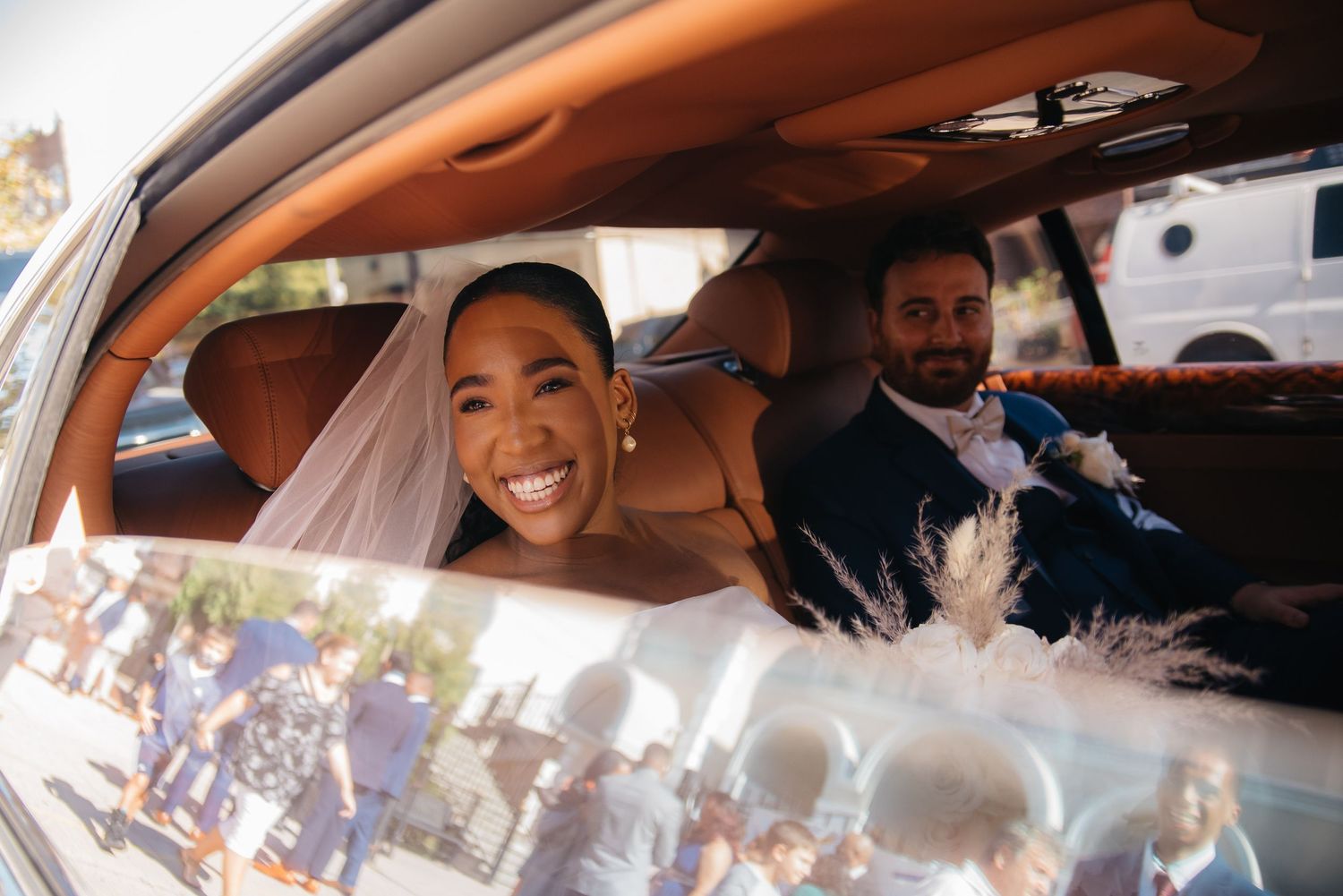 A radiant bride beams with joy while seated in a luxury car.