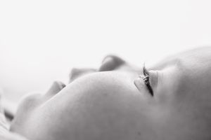 Close-up black and white portrait of a sleeping baby with delicate features and soft skin.