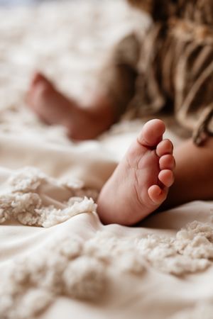 Close-up of a newborn baby's tiny foot resting on a soft white textured blanket.