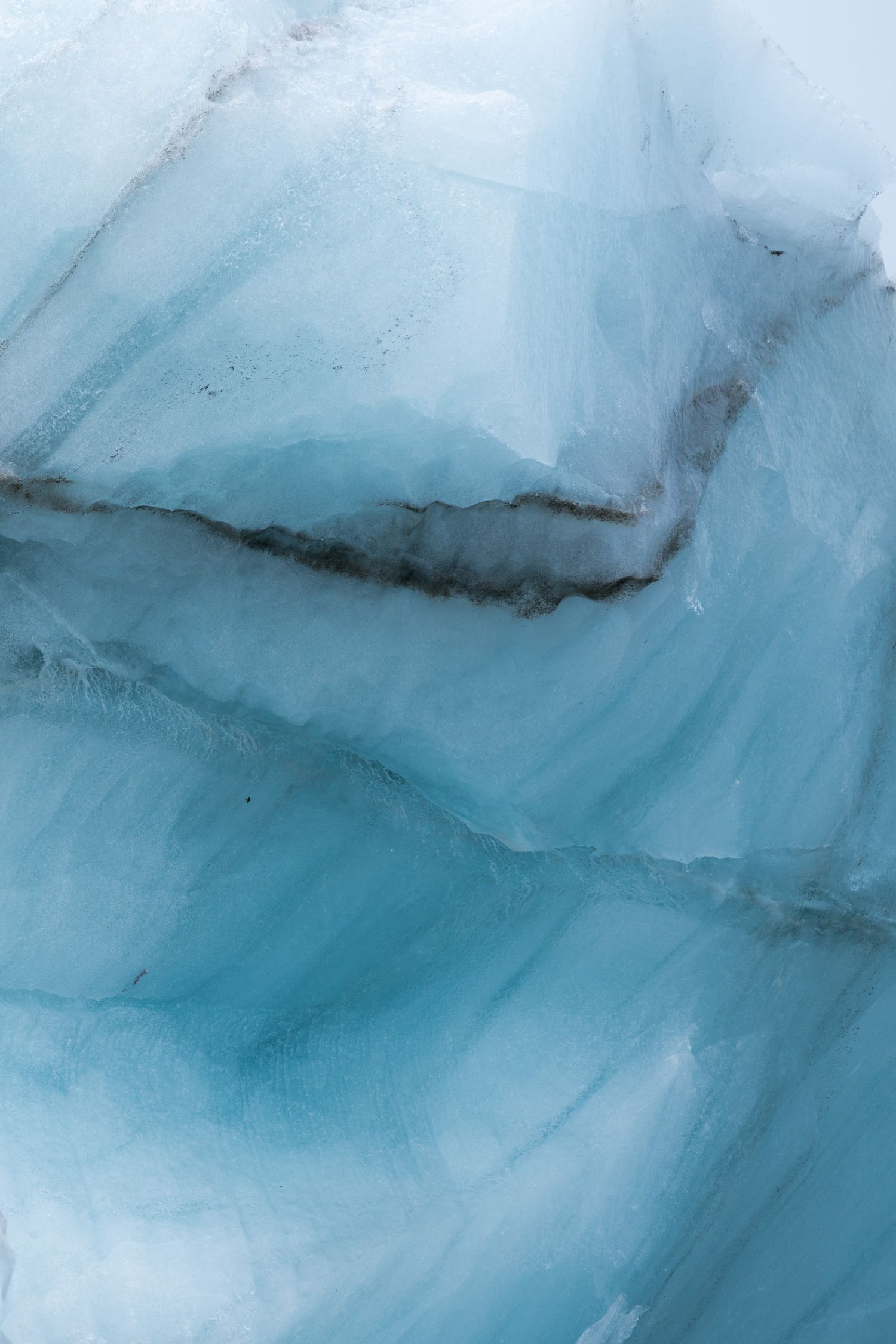 Plans de fracture d'une glace bleue traversée d'une veine de sédiments sombres