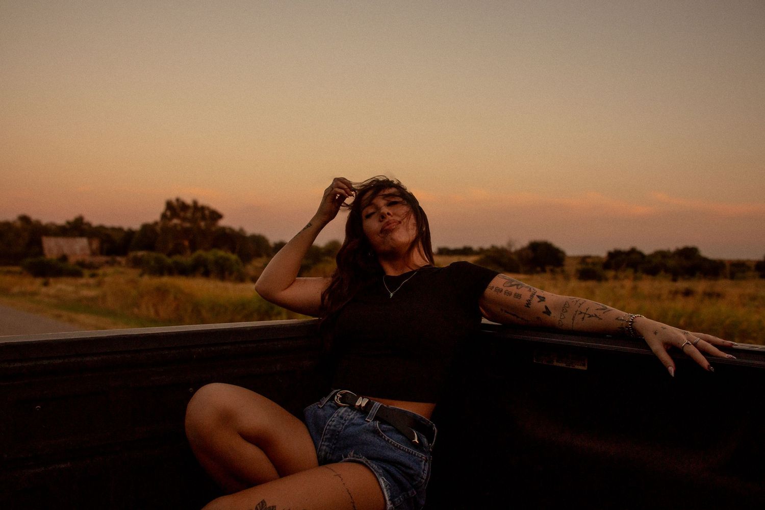 Woman posing in the bed of a pickup truck at sunset during an outdoor portrait session in Oklahoma City.