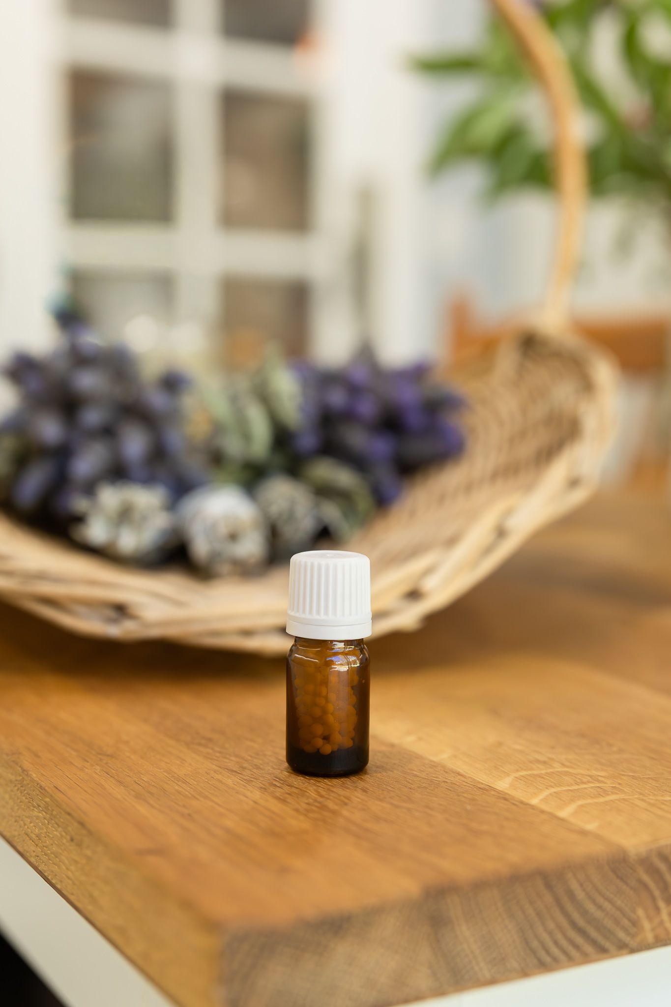 Small amber bottle on a wooden table, with dried botanicals softly blurred behind it in Kelmscott in a branding photography session.
