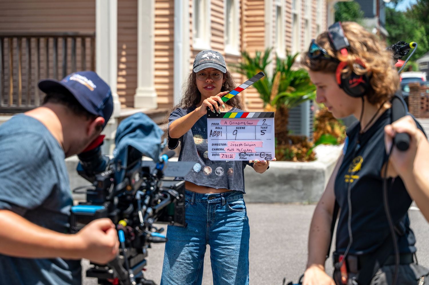 A cameraman wearing headphones operates a professional cinema camera rig on a film set.