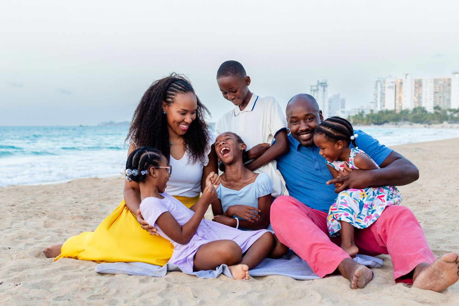Family portrait. Mom, dad, and four kids seated on the beach in Isla Verde, Carolina, Puerto Rico.