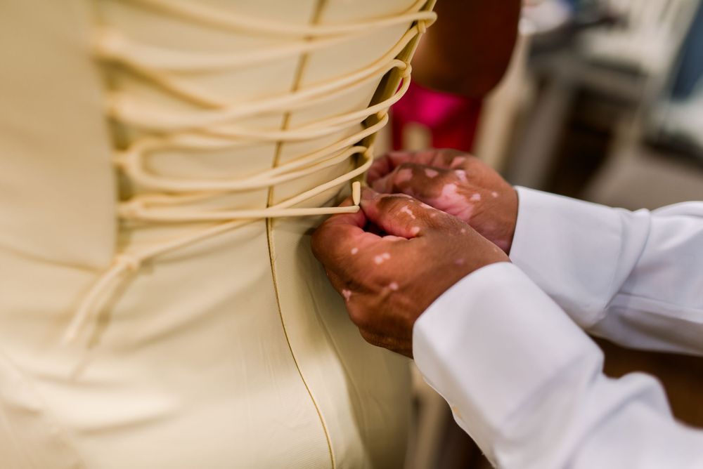 Close-up of hands lacing up a cream corset wedding dress on a bridal mannequin in a bridal boutique.