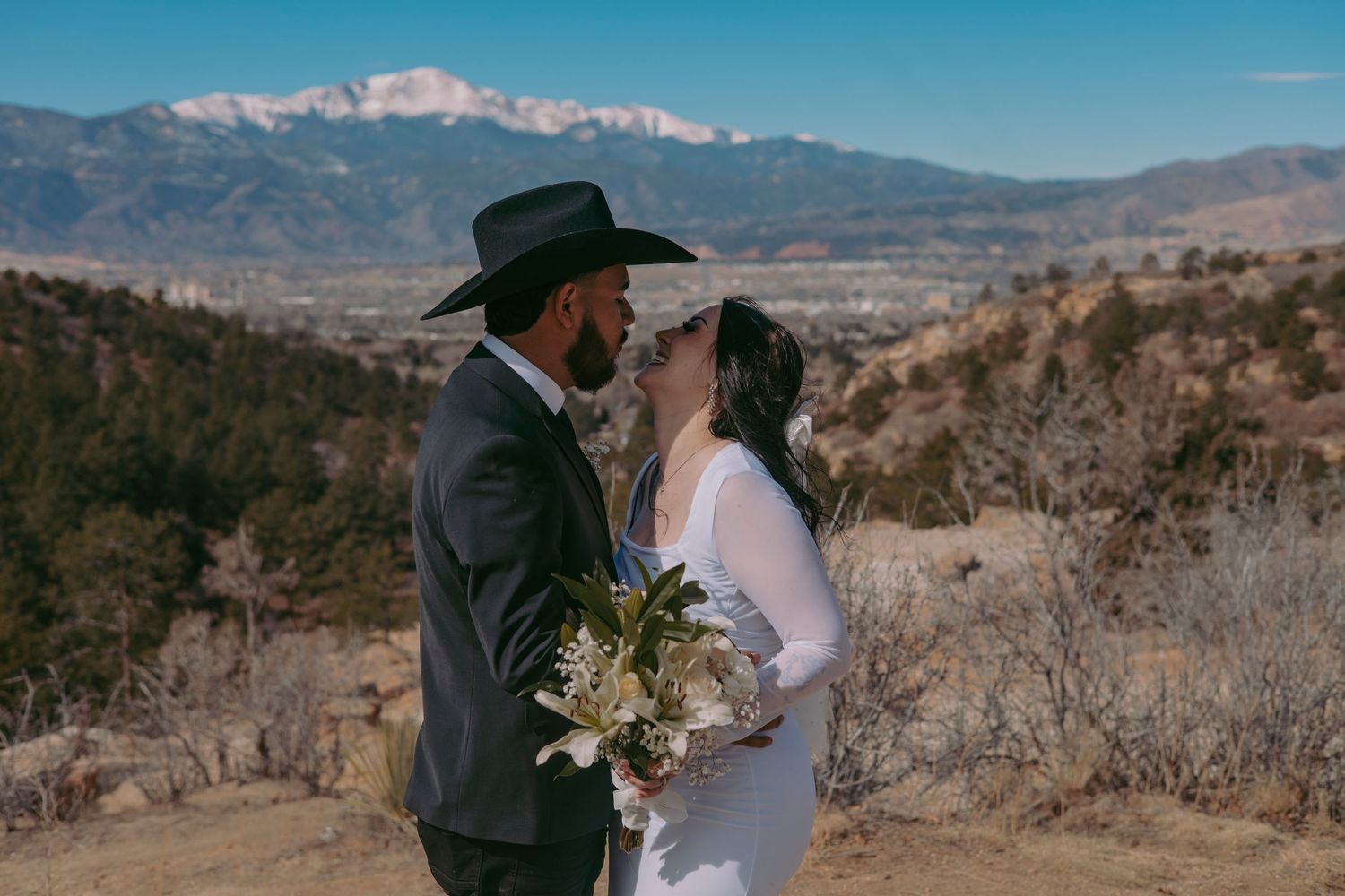 Bride and groom sharing a romantic moment with snow-capped mountains in the background.